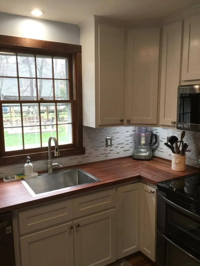 Kitchen with dark wood countertop and white cabinetry
